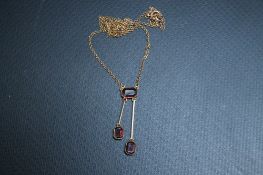 A STYLISH 9CT GOLD DROPPER NECKLACE, set with three emerald cut style garnets - two independently