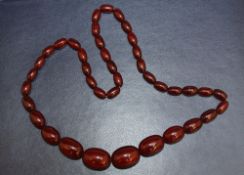 A STRING OF GRADUATING CHERRY AMBER BEADS, largest W 2.5 cm