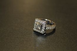 A HALLMARKED HANDMADE 18 CARAT WHITE GOLD DIAMOND RING, set with a central Princess cut diamond of