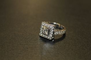 A HALLMARKED HANDMADE 18 CARAT WHITE GOLD DIAMOND RING, set with a central Princess cut diamond of