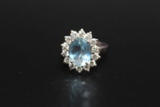 A HALLMARKED 18 CARAT WHITE GOLD AQUAMARINE AND DIAMOND CLUSTER RING, the central Aquamarine being