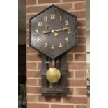 AN UNUSUAL ARTS AND CRAFTS STYLE WALLCLOCK, the hexagonal face with brass numerals, pendulum, H 81