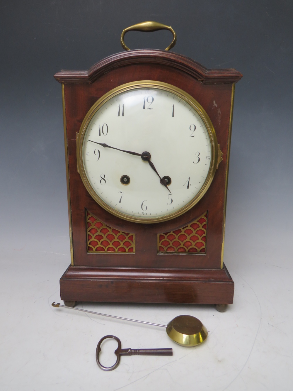 AN EARLY 20TH CENTURY MAHOGANY CASED BRACKET CLOCK, having a break arch case and padded top with
