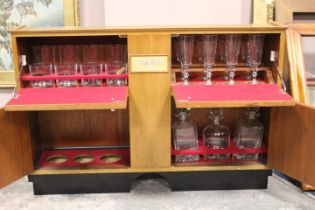 A VINTAGE TEAK AUSTIN FITTED TRAVELLING DRINKS CABINET, having four compartments with assorted