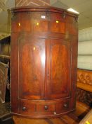 A GEORGIAN MAHOGANY BOW FRONT CORNER CUPBOARD