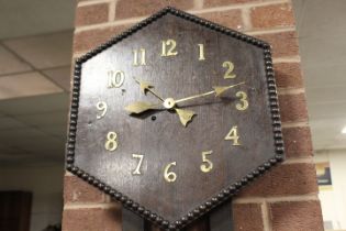 AN UNUSUAL ARTS AND CRAFTS STYLE WALLCLOCK, the hexagonal face with brass numerals, pendulum, H 81