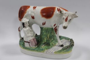 A STAFFORDSHIRE STYLE FLAT BACK FIGURE OF A COW AND MILKMAID A/F