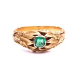 A floral engraved dress ring set with an emerald, collet-set with an emerald-cut emerald in bright