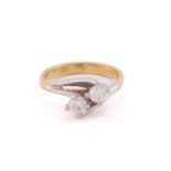 A two stone diamond crossover ring; the round brilliant cut diamonds in four claw mounts to bi-
