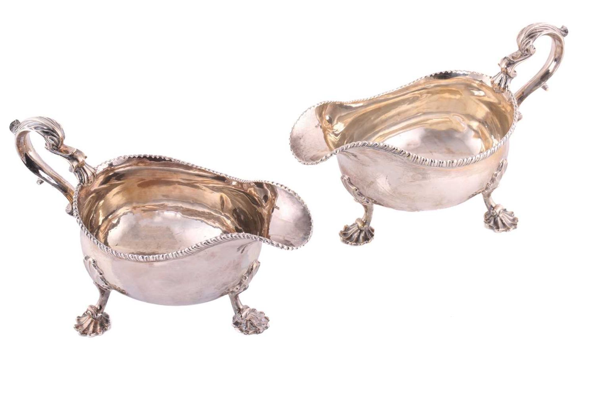 A pair of George II silver sauce boats; with gadrooned borders and leaf capped double scroll