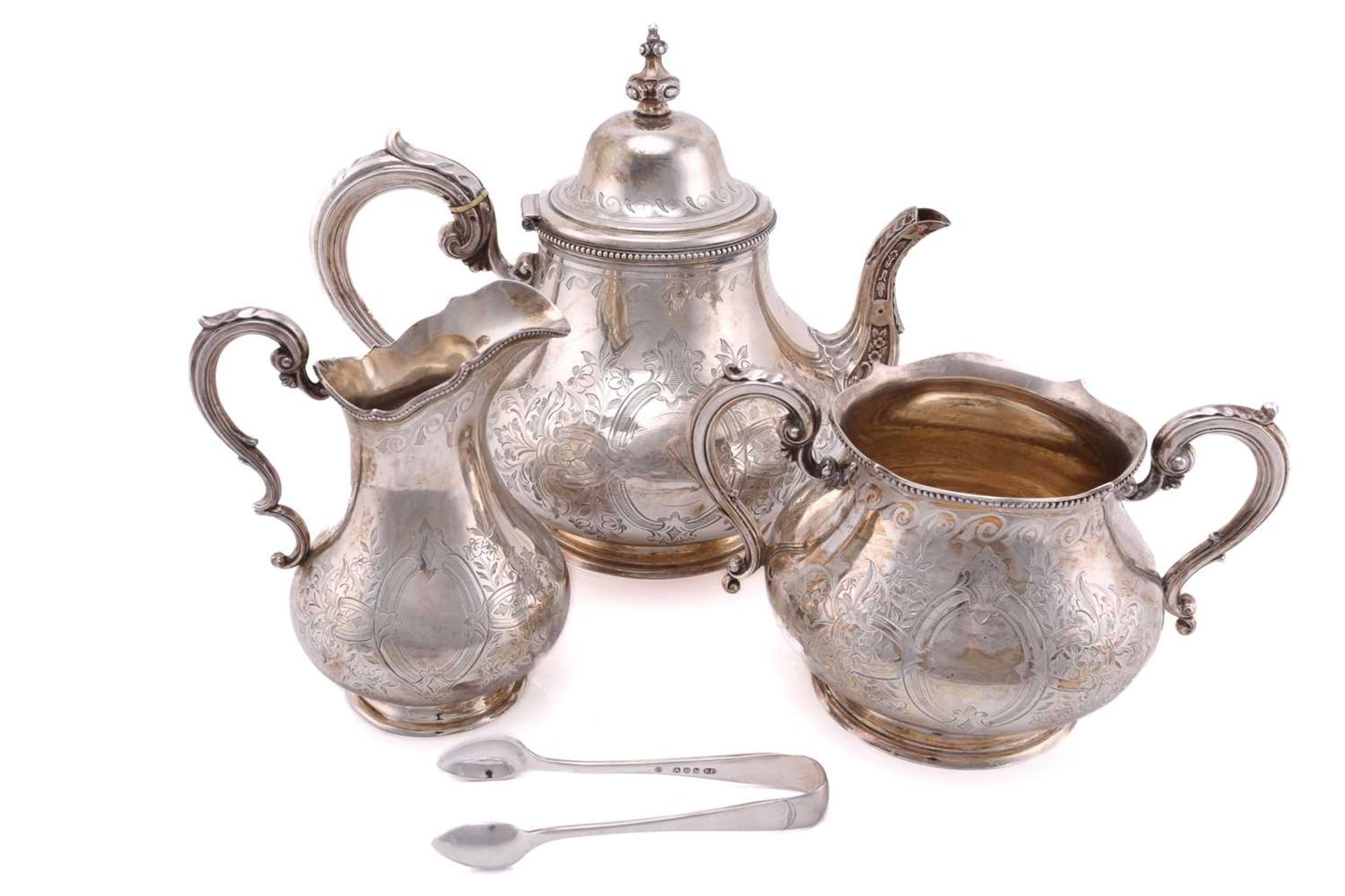 A Victorian silver three-piece tea service and sugar tongs of mixed date but the corresponding