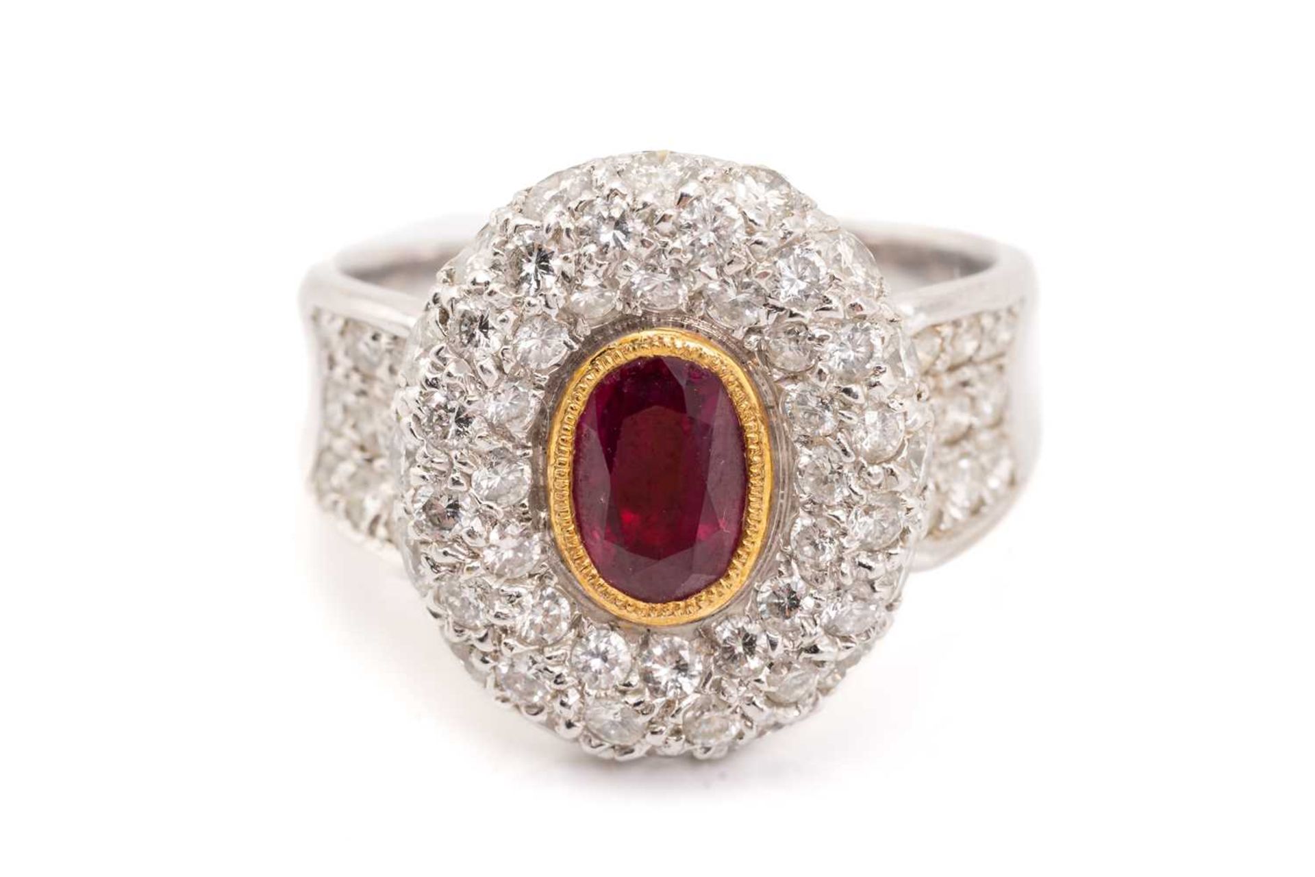 A synthetic ruby and diamond cluster style ring, featuring a rub over set oval cut synthetic ruby