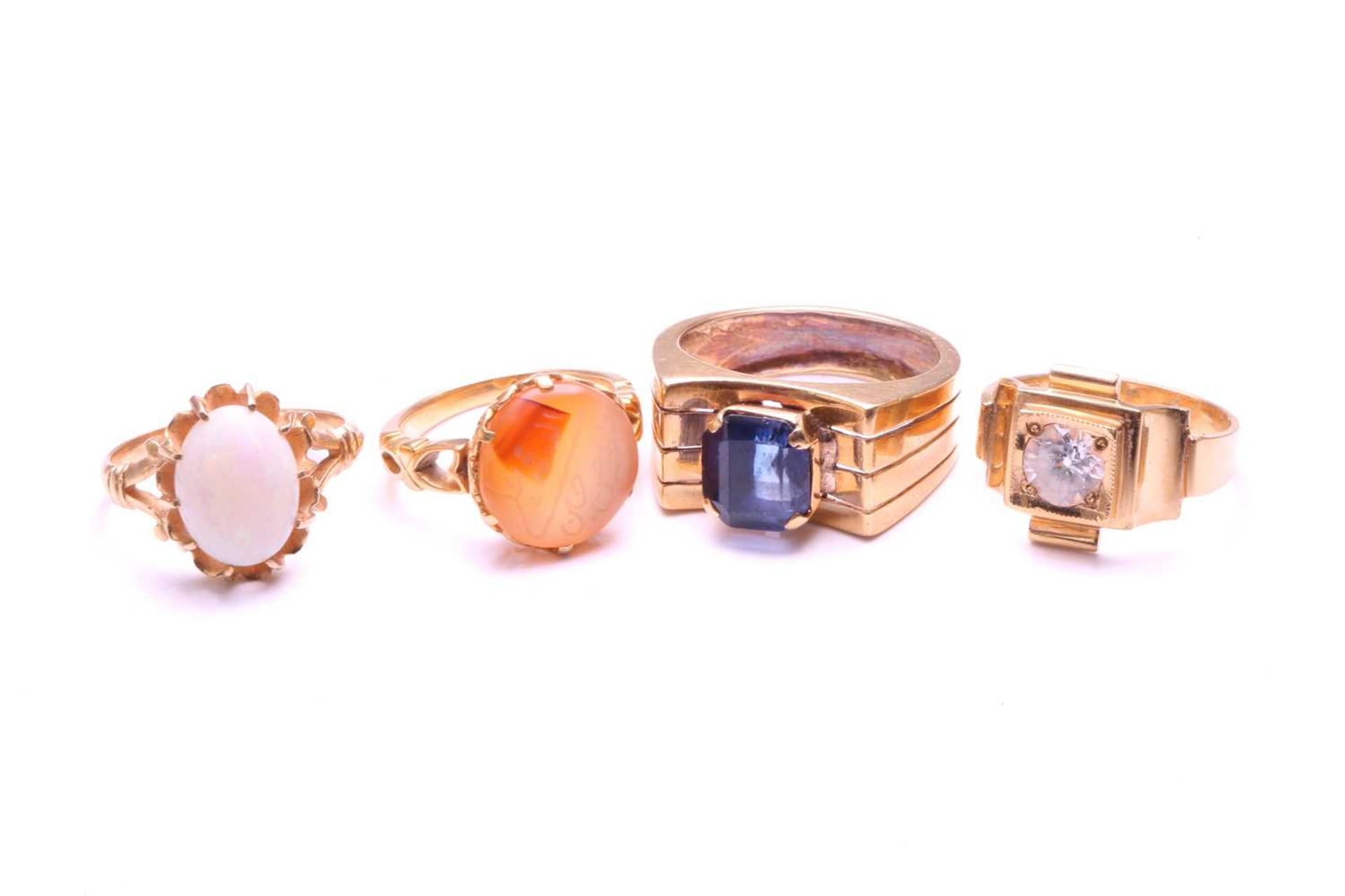 Four gem-set rings, including an Aqeeq ring with a round carnelian in coronet setting, engraved with