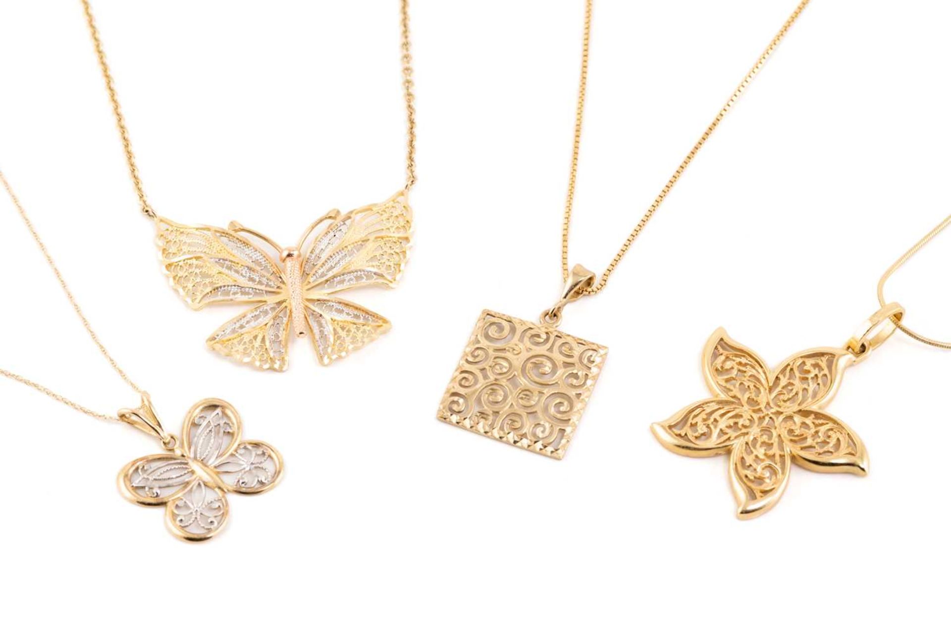 A collection of four pieced-out pendants on chains, including a 10ct gold pierced butterfly