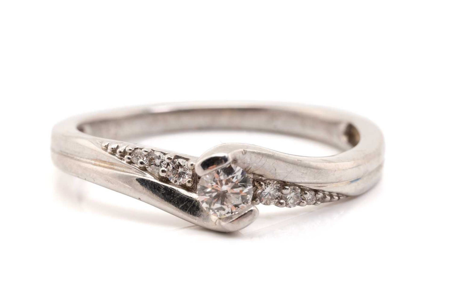 A diamond set cross-over ring, featuring a central round brilliant-cut diamond measuring 3.