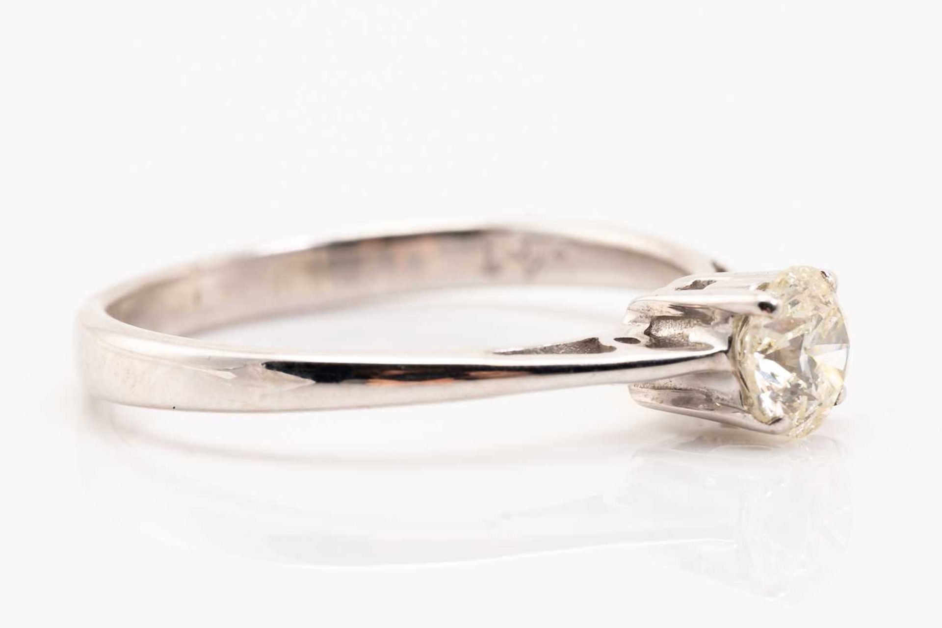 A diamond single stone ring; the round brilliant cut diamond in four claw mount, to a plain polished - Image 2 of 5