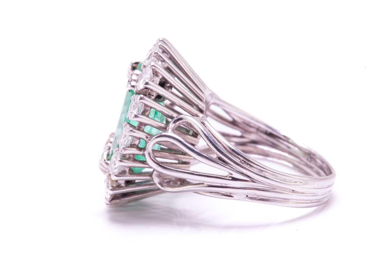 An emerald and diamond entourage ring, centred with an emerald-cut emerald of pale bright bluish- - Image 6 of 12