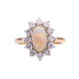 An opal and diamond entourage ring in 18ct gold, featuring an oval precious opal cabochon of 9.2 x