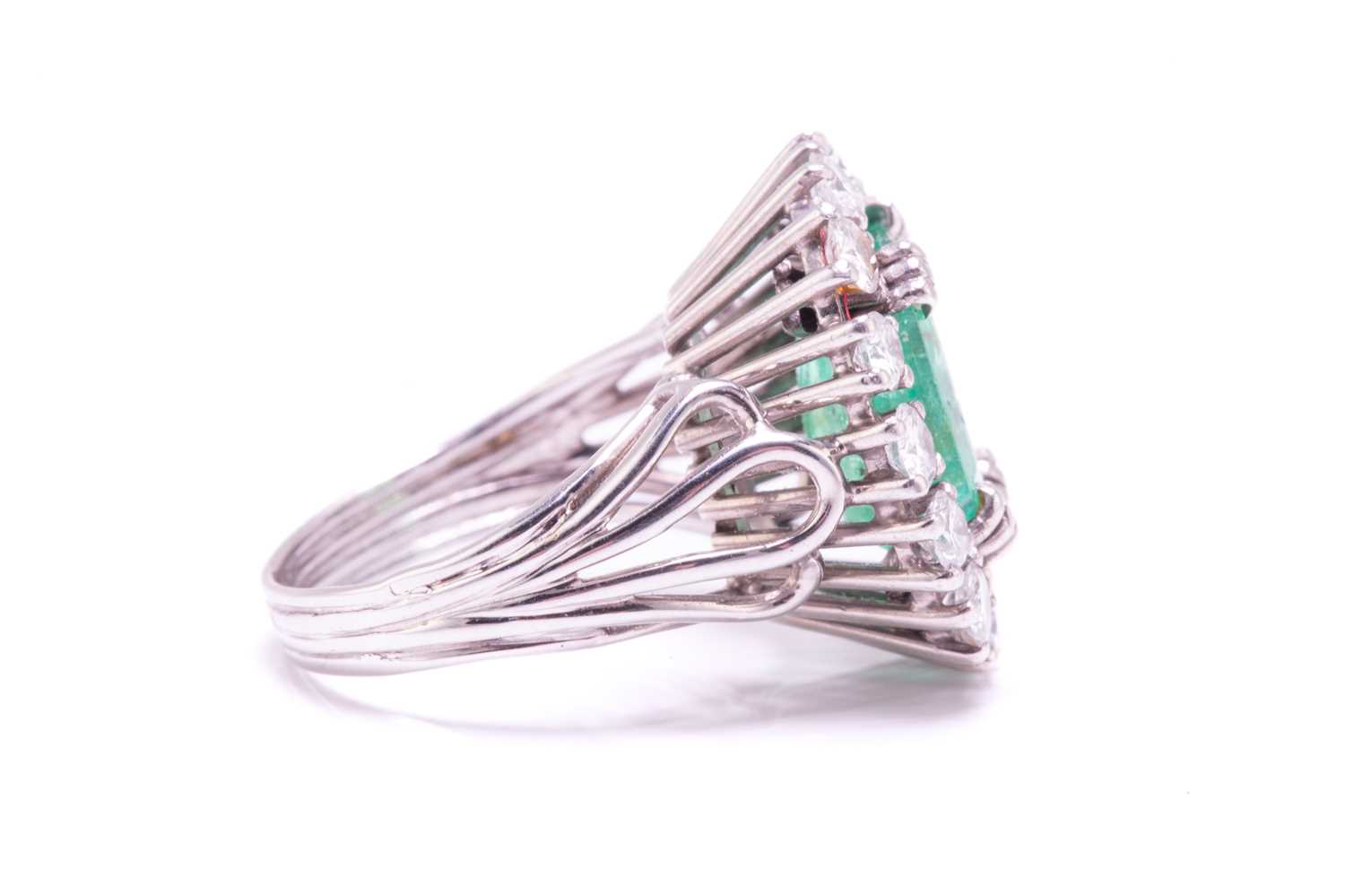 An emerald and diamond entourage ring, centred with an emerald-cut emerald of pale bright bluish- - Image 10 of 12