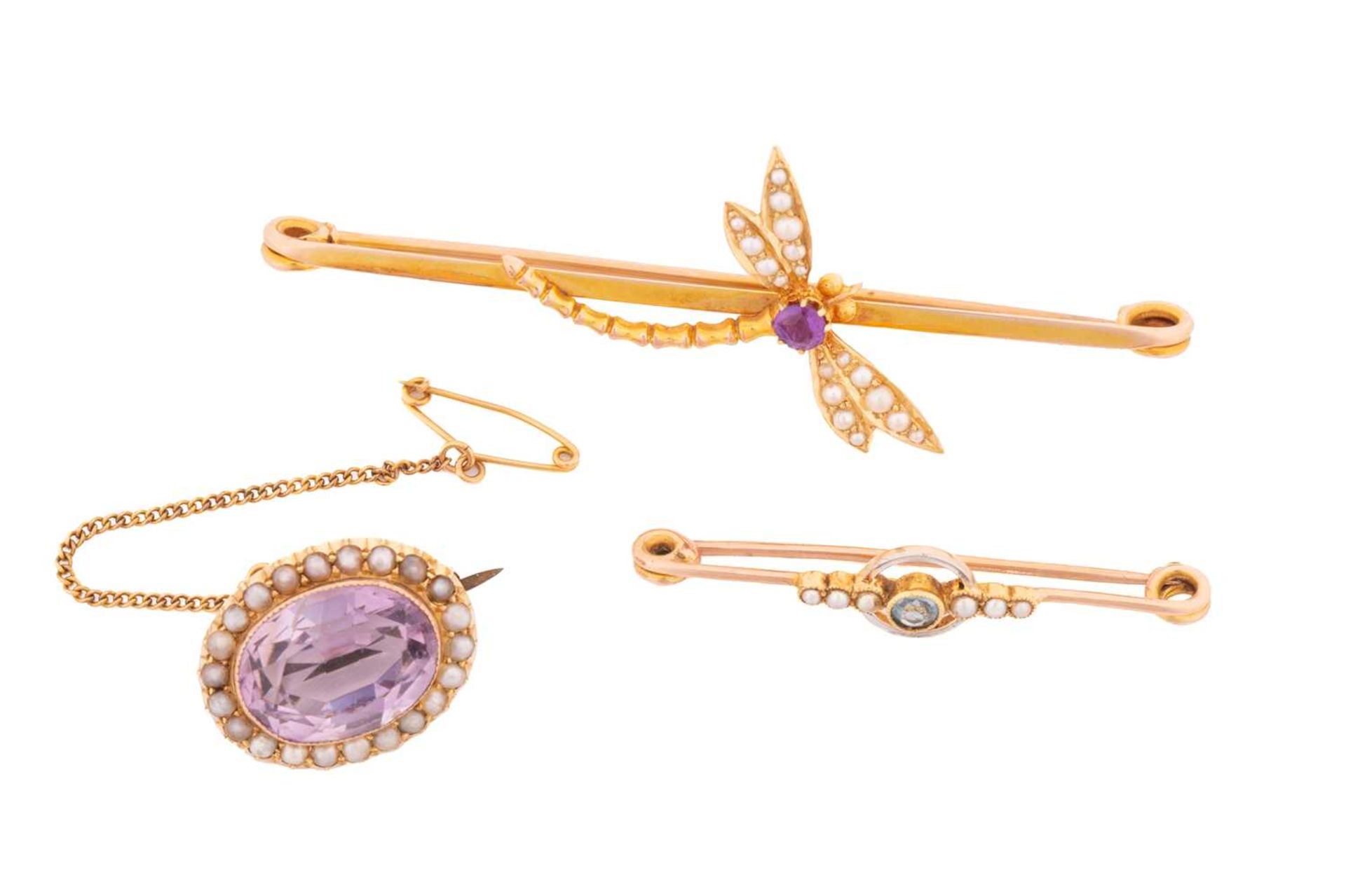 Three gem-set brooches with seed pearls; the first contains an oval-cut amethyst with pale purple