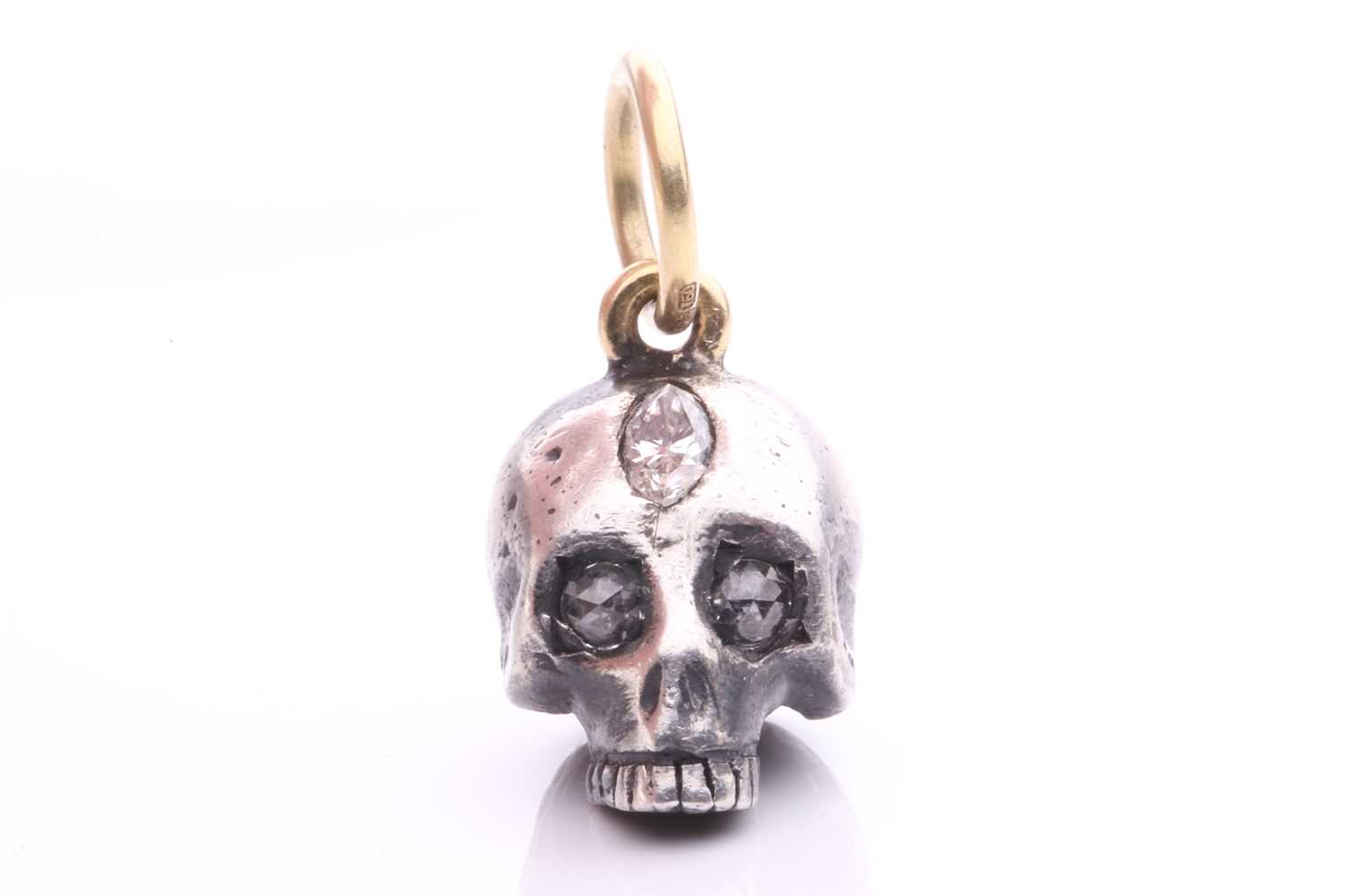 A diamond-set skull charm pendant in silver and 18ct gold, a sculpted hollow skull with eyes set