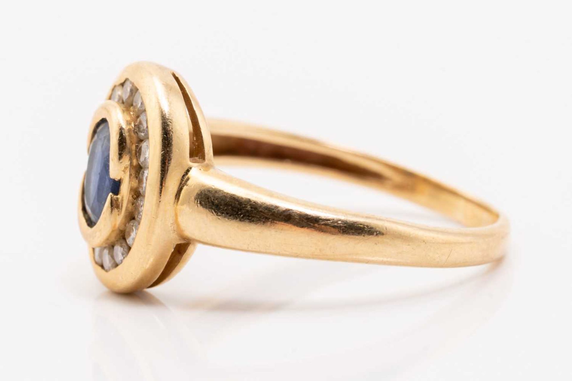 A yellow metal, sapphire and diamond halo ring, centred with an oval-cut sapphire in collet, - Image 2 of 4