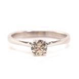 A diamond single stone ring; the round brilliant cut diamond in four claw mount, to a plain polished