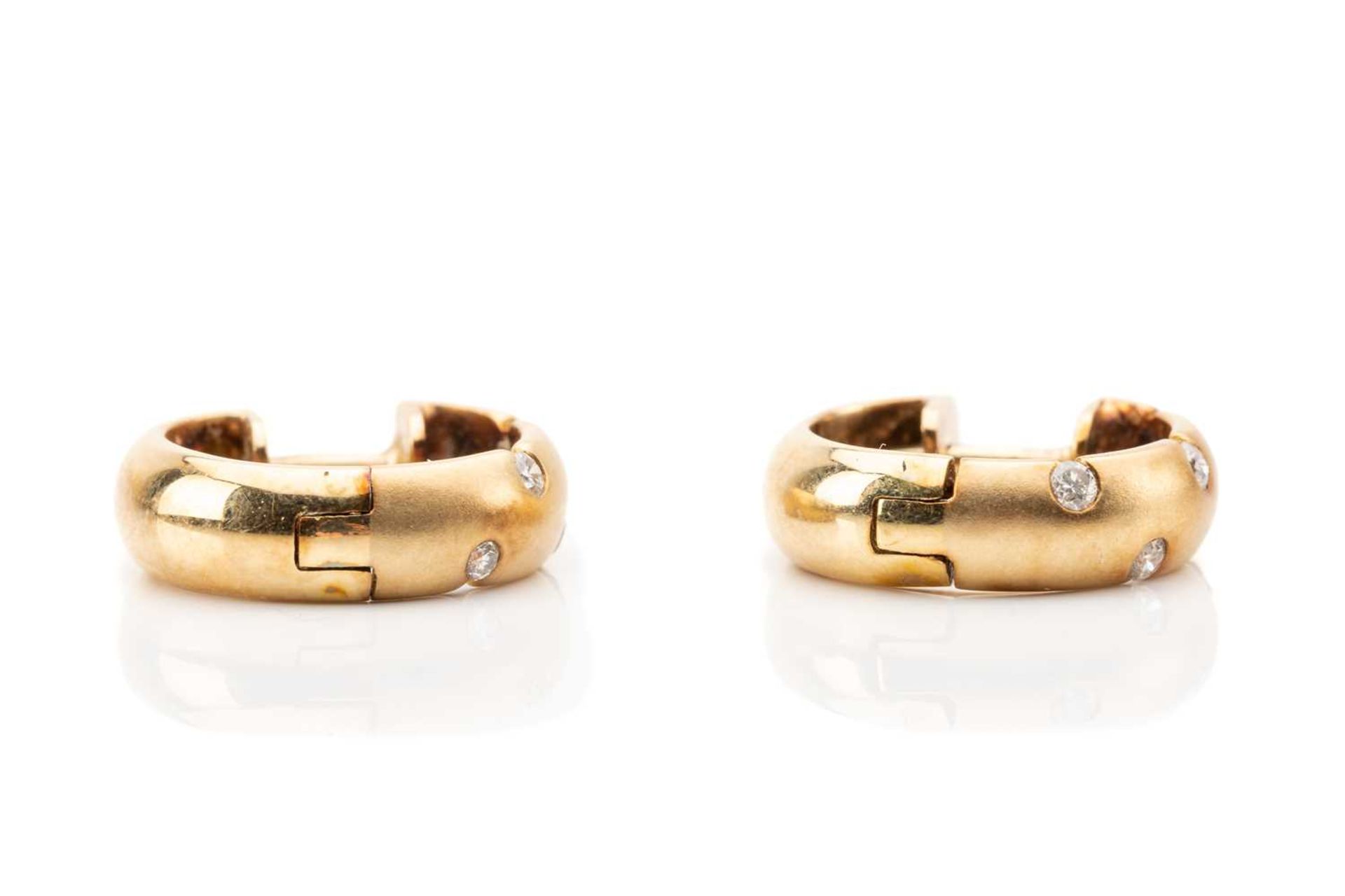 A pair of diamond set huggy hoop earrings, featuring sunk set round brilliant cut diamond in