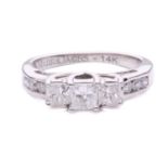 A three-stone princess cut ring with a diamond set shoulder, with three claw set princess cut