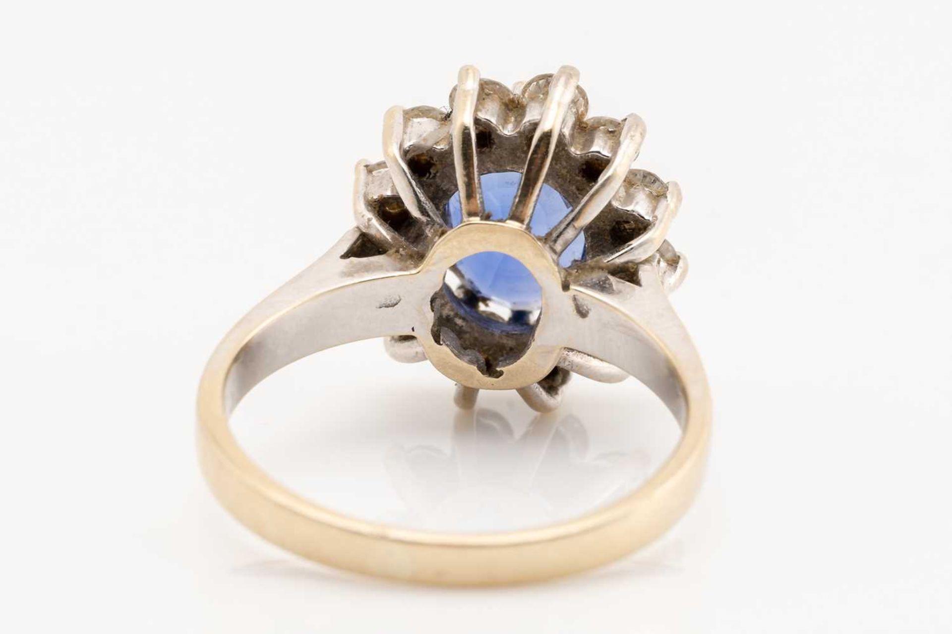 A sapphire and diamond cluster ring; the oval cut sapphire in claw mount above a border of twelve - Image 5 of 6