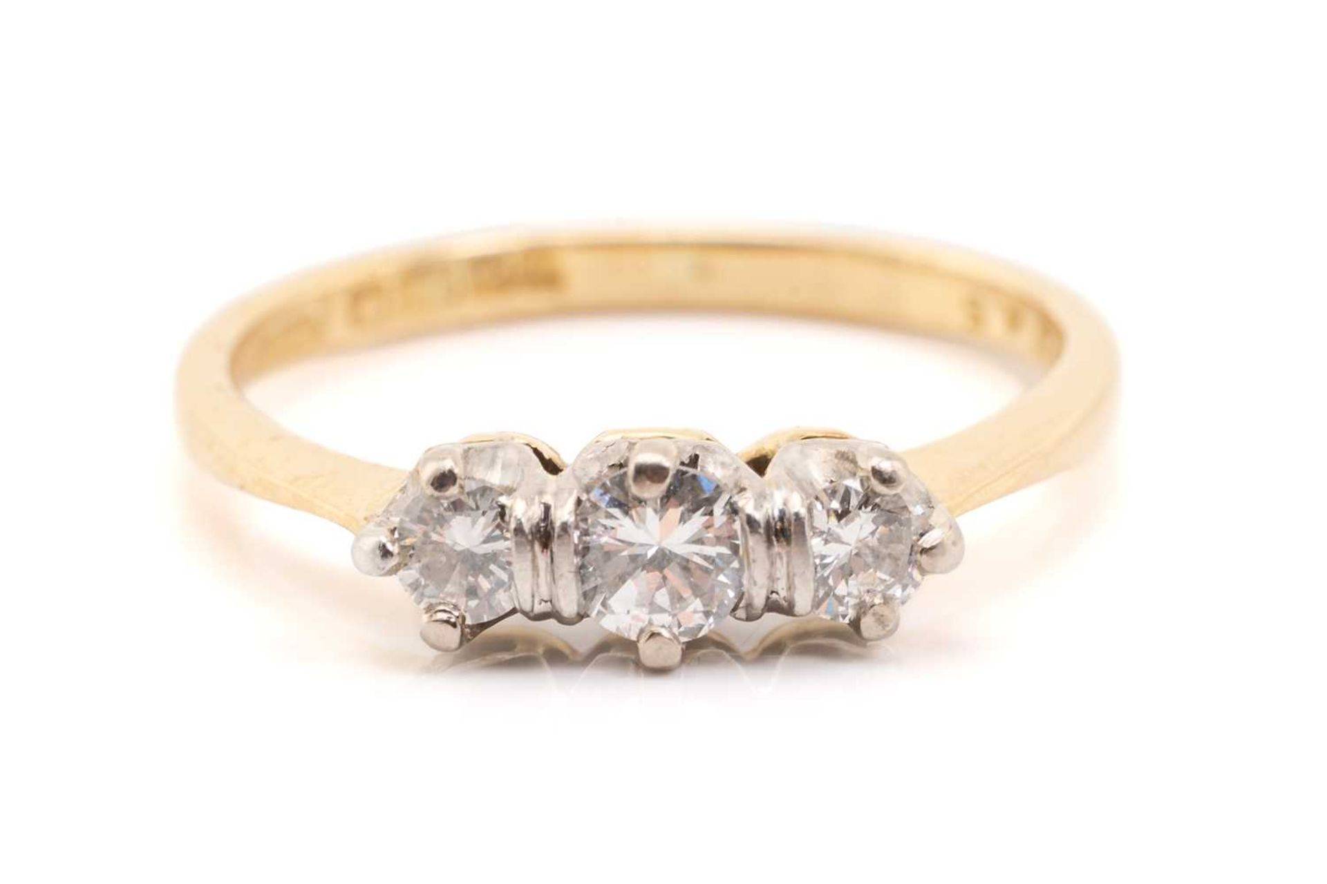 A yellow gold and diamond three stone half hoop diamond ring; the slightly graduated round brilliant