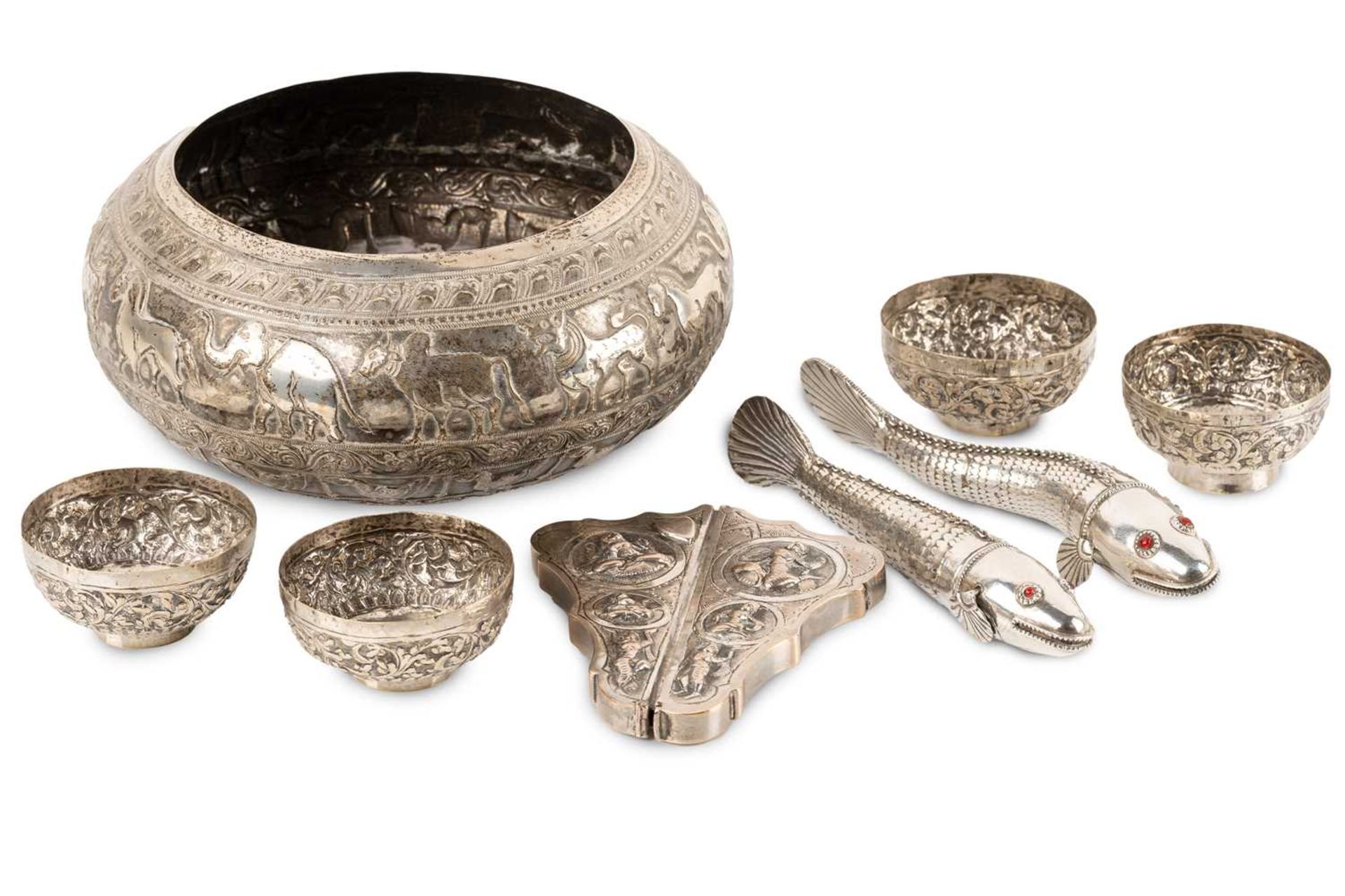 A Burmese white metal circular bowl with an inverted rim embossed with galleries of promenading