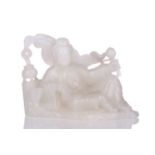 A Chinese white jade figure of Guanyin, seated in a recumbent pose with lotus flower in her left