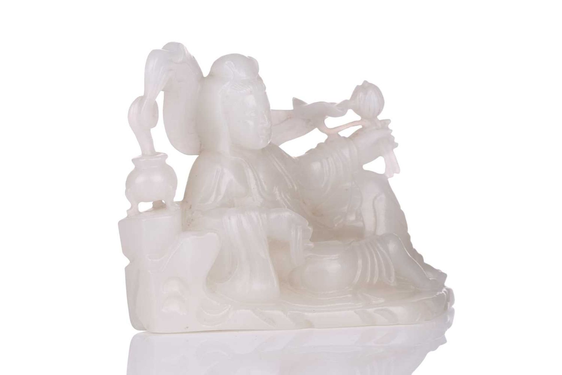 A Chinese white jade figure of Guanyin, seated in a recumbent pose with lotus flower in her left - Image 2 of 14