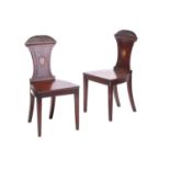 A pair of George III, late 18th-century mahogany hall chairs, with caved sunflower, arched