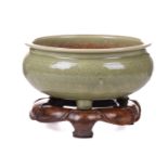 A Chinese celadon circular censer with diaper pattern decoration on three pad feet, with a carved