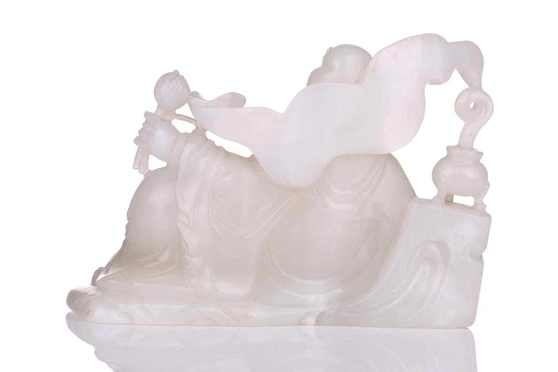 A Chinese white jade figure of Guanyin, seated in a recumbent pose with lotus flower in her left - Bild 3 aus 14