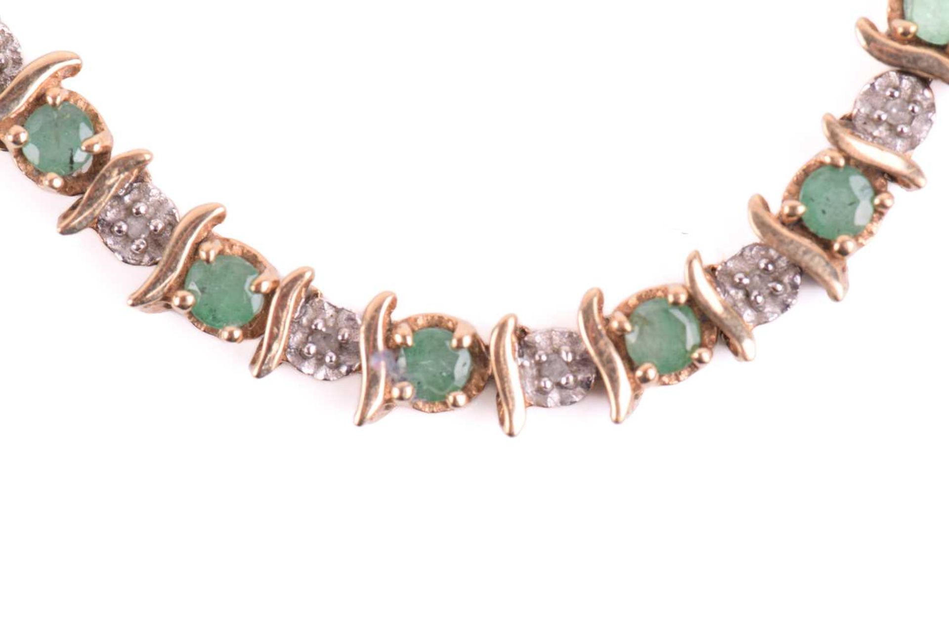 An emerald and diamond line bracelet in 9ct gold, with alternating circular-cut emeralds and - Image 5 of 7