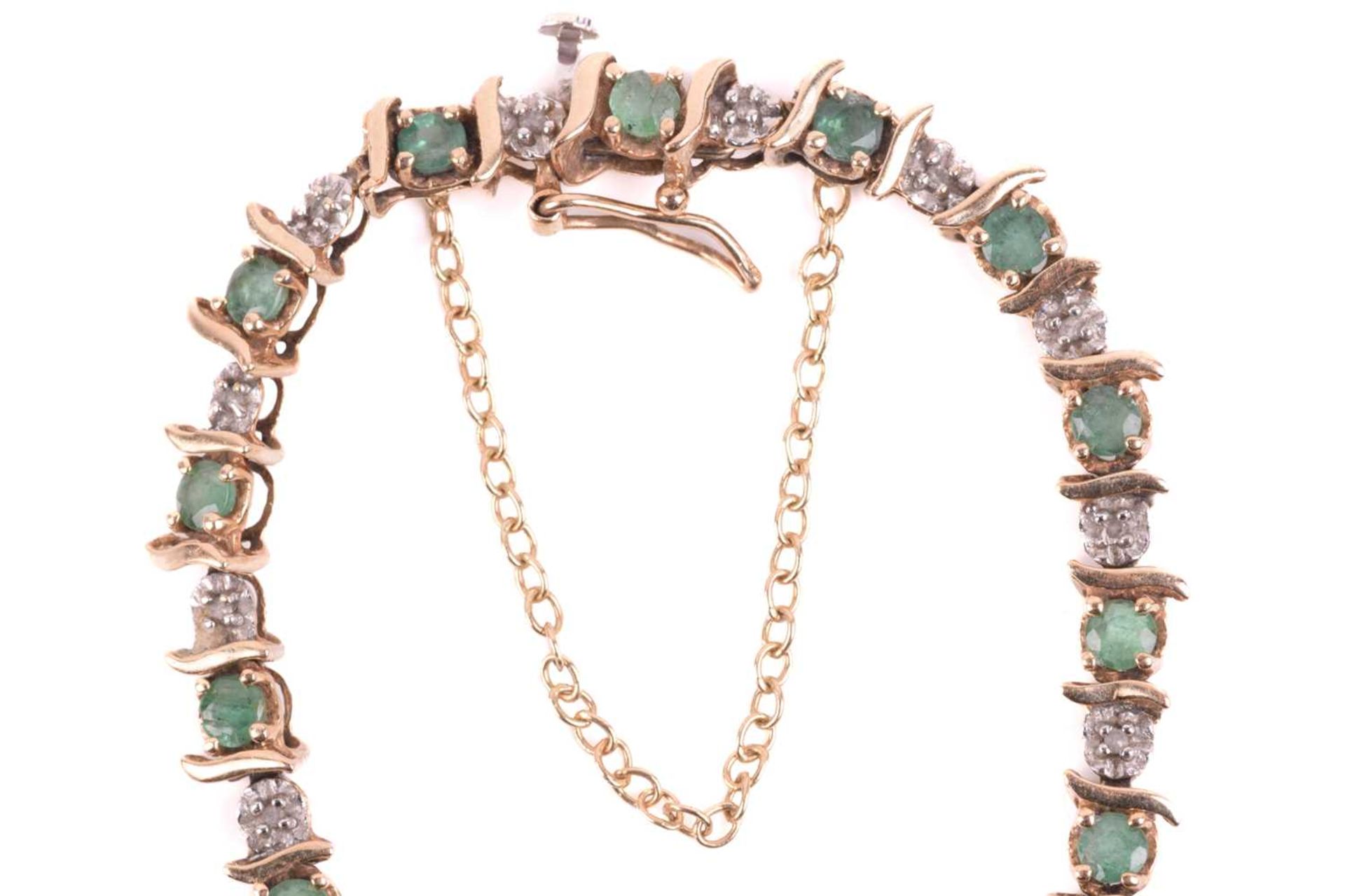 An emerald and diamond line bracelet in 9ct gold, with alternating circular-cut emeralds and - Image 4 of 7