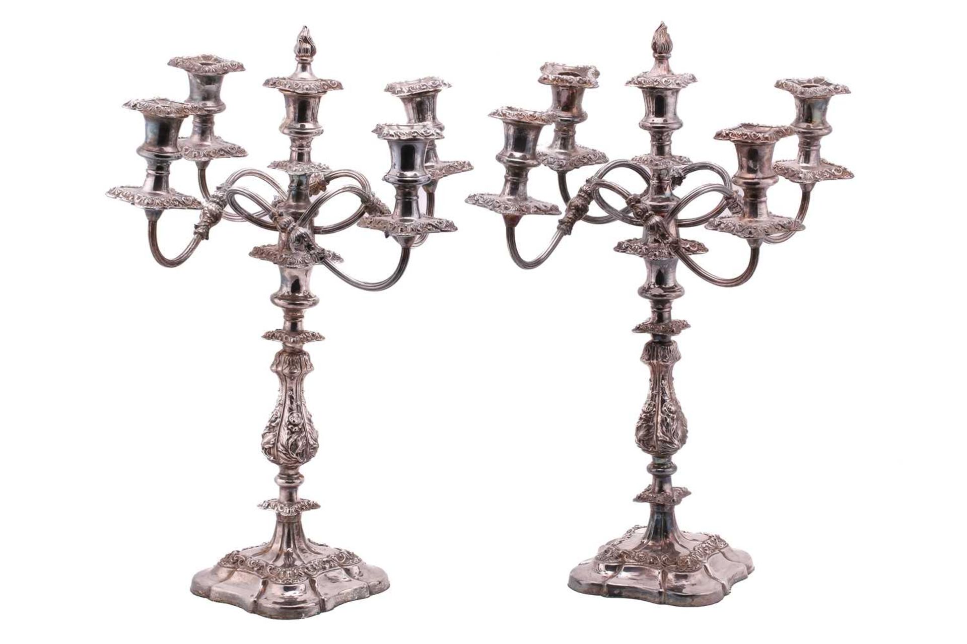 A pair of silver plated candelabra each with a central detachable flame finial in two sections