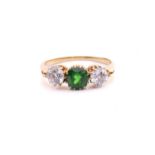 A tsavorite and diamond three-stone ring, centred with a circular-cut tsavorite in intense green