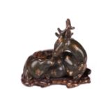 A Chinese porcelain simulated bronze figure of a recumbent stag with a sprig of lingzhi, the green