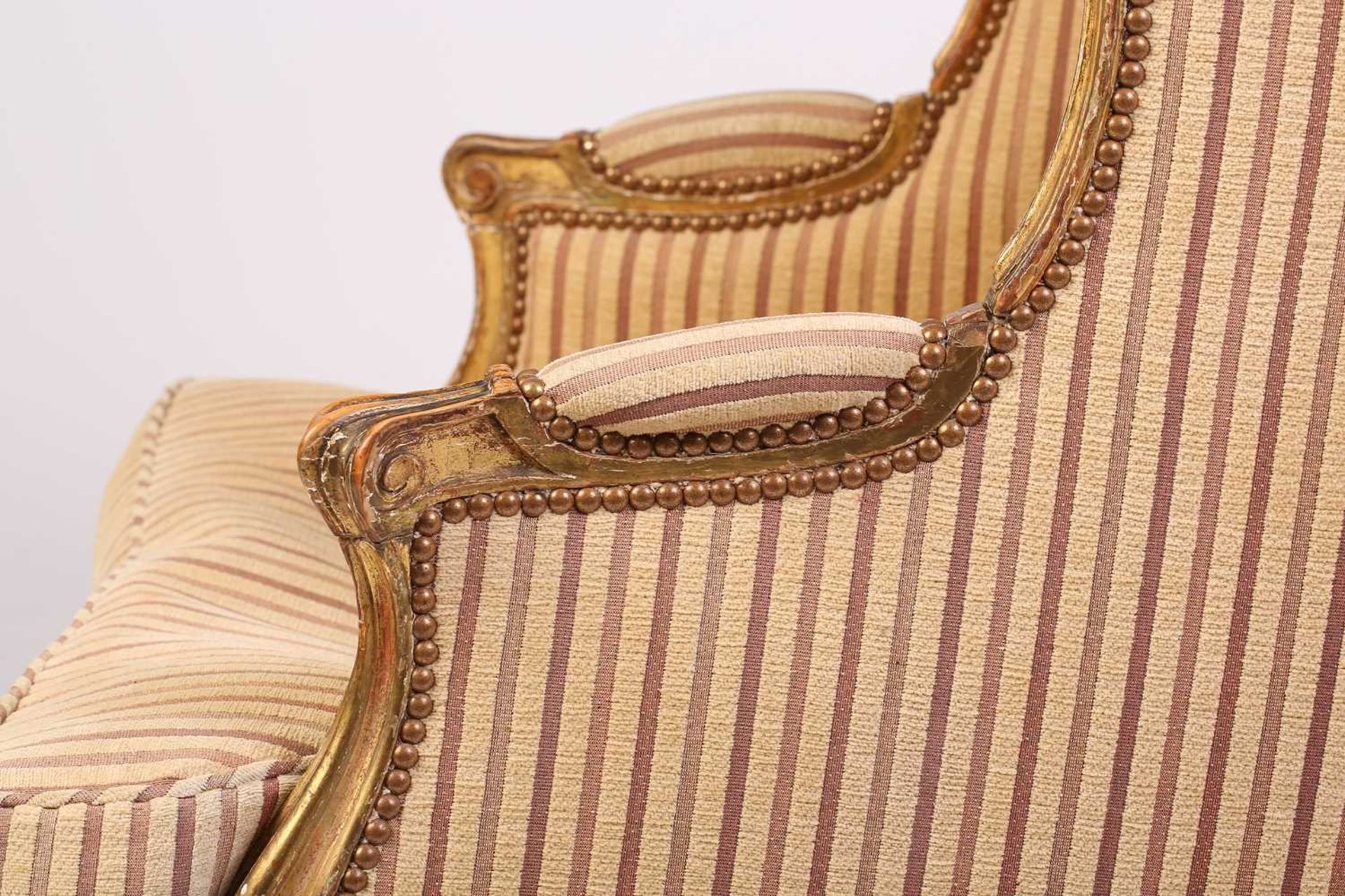 A Louis XV style bergere wing chair, 19th century, with carved wood and gilt gesso frame and striped - Image 8 of 9