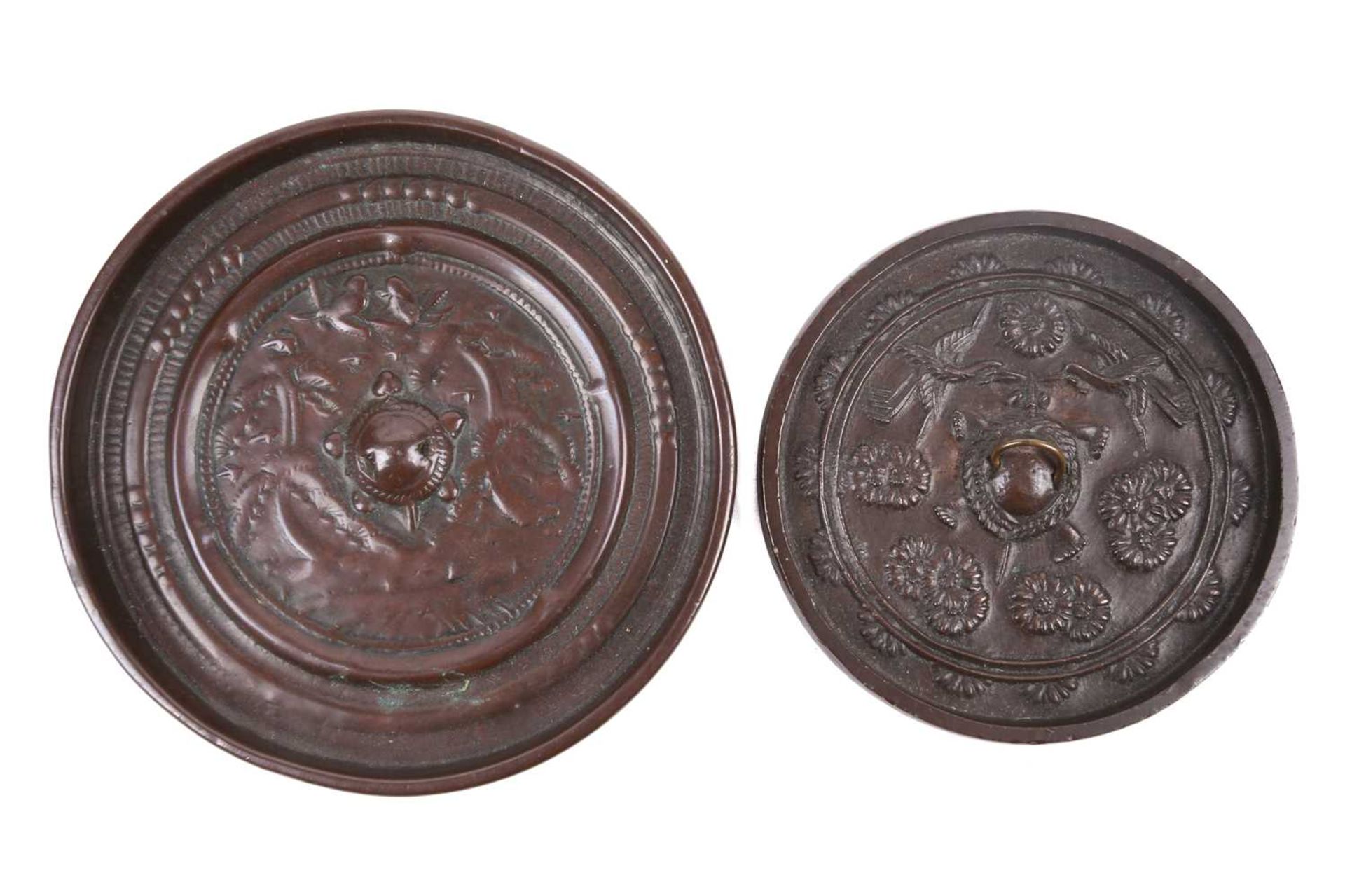 A Japanese bronze mirror, 19th century, relief cast with a central pierced tortoiseshell boss,