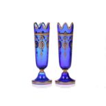 A pair of blue glass and gilt-decorated vases, of turreted form on a circular foot, the gilt-swag