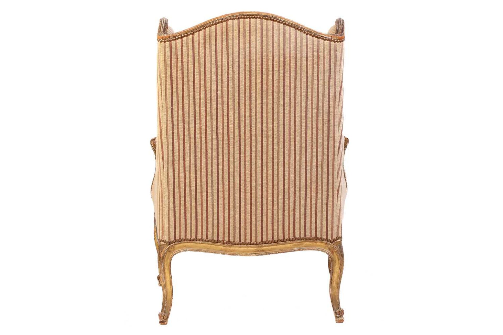 A Louis XV style bergere wing chair, 19th century, with carved wood and gilt gesso frame and striped - Image 7 of 9