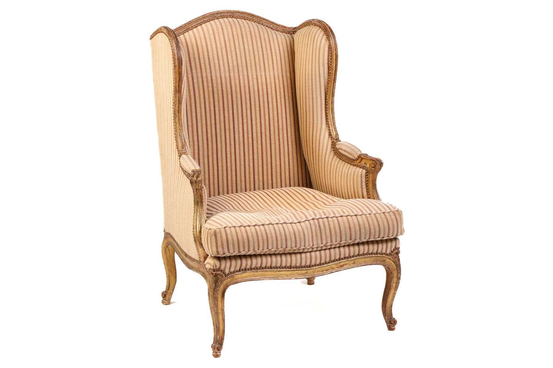 A Louis XV style bergere wing chair, 19th century, with carved wood and gilt gesso frame and striped