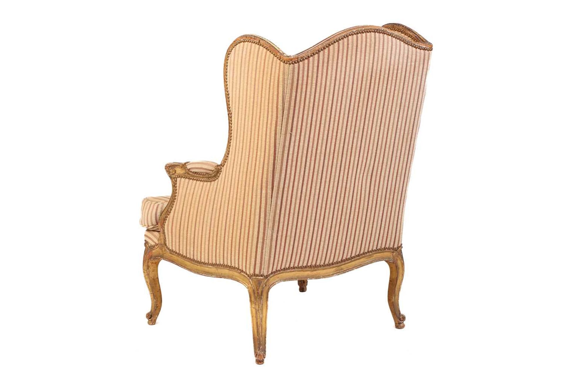 A Louis XV style bergere wing chair, 19th century, with carved wood and gilt gesso frame and striped - Image 6 of 9