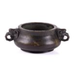 A Chinese bronze censer, with thick walled compressed body, with applied elephant mask handles,