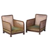 A pair of 1920s oak cane back bergere armchairs, with carved frieze decoration, lacking cushions, 74